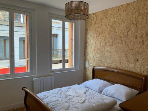 a bedroom with a bed with two pillows and two windows at Villa Georges in Le Tréport