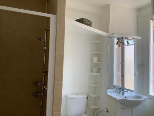a white bathroom with a toilet and a sink at Villa Georges in Le Tréport