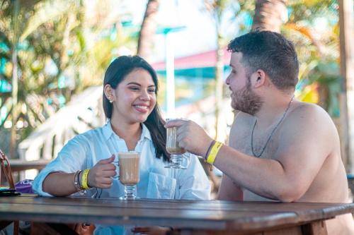un hombre y una mujer sentados en una mesa con bebidas en Hotel Viña del Mar Omoa, en Omoa