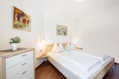 een witte slaapkamer met een bed en een dressoir bij Tischlerhof - Typ C in Tirolo