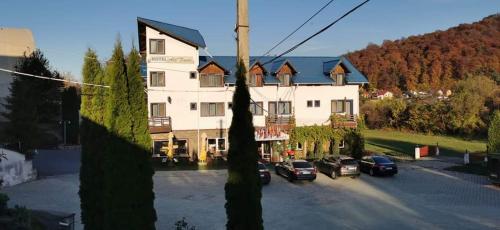 a large white building with cars parked in a parking lot at HOTEL ALL TIMES in Timisul de Jos