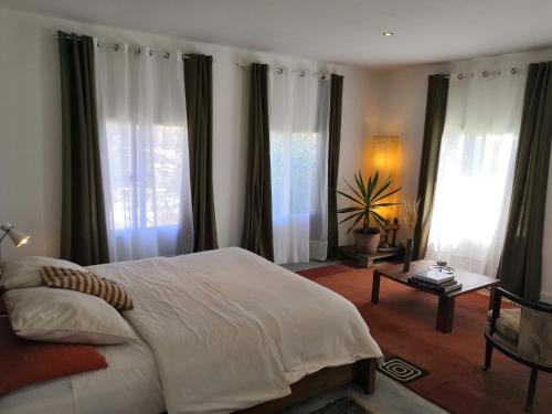 Maison d'Hôtes Mandrosoa في أنتاناناريفو: غرفة نوم بسرير ابيض ونوافذ كبيرة