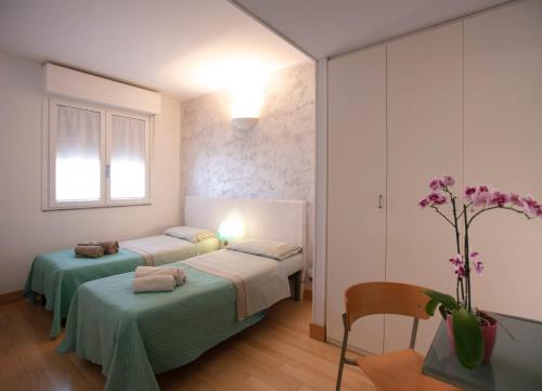 a bedroom with two beds and a table with a vase of flowers at Giardini e Mare in Quartu SantʼElena