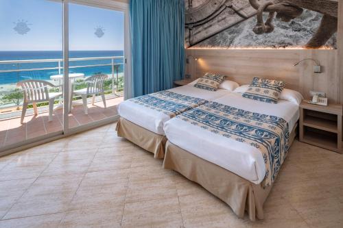 a bedroom with a bed with a view of the ocean at GHT Maritim in Calella