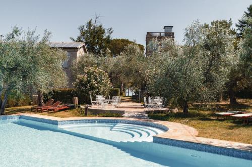 a swimming pool in a yard with trees at Il Pignocco Country House in Santa Veneranda