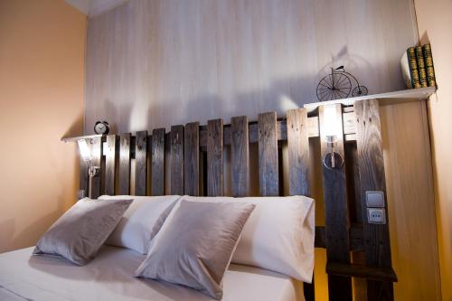 uma cama com almofadas brancas e uma cabeceira em madeira em Ca La Garranxera em Porrera