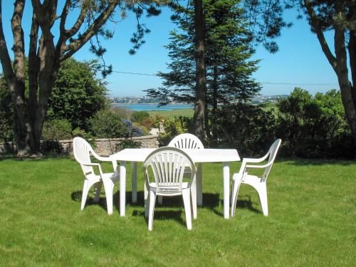 a white table and four chairs in the grass at Holiday Home Avel Vor by Interhome in Saint-Pol-de-Léon