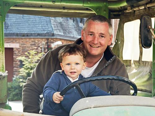 a man holding a small child sitting on a tractor at WeinBergHotel Nalbach in Reil