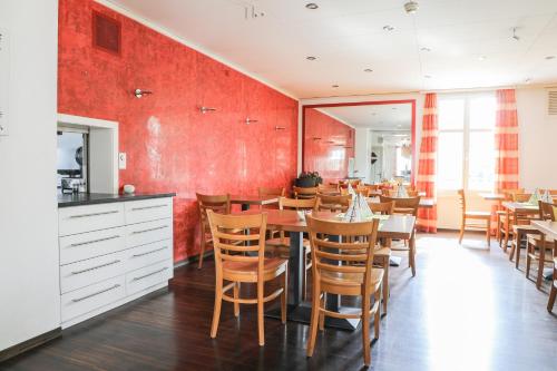 Niederuzwil的住宿－hotel löwen，一间拥有红色墙壁和桌椅的用餐室