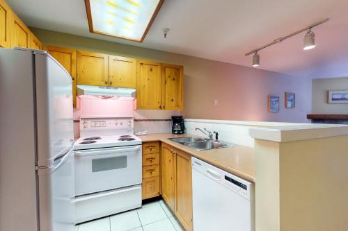 una cocina con electrodomésticos blancos y armarios de madera en Marketplace Lodge, en Whistler
