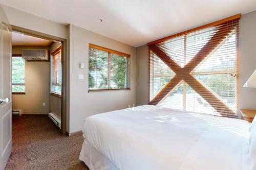 ein Schlafzimmer mit einem weißen Bett und einem großen Fenster in der Unterkunft Town Plaza Suites in Whistler