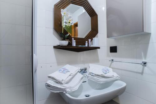La salle de bains blanche est pourvue d'un lavabo et d'un miroir. dans l'établissement La Pìcola Cèsa de Sèn Nicolò, à Mazzin