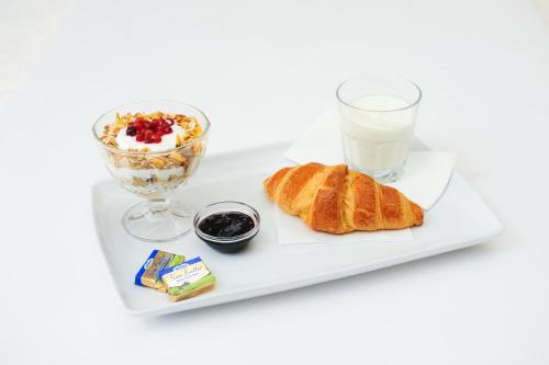 a plate of breakfast food with a glass of milk at Hotel Stil in Cluj-Napoca