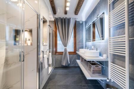 baño con 2 lavabos y ducha de cristal en Loggia Rialto Apartments, en Venecia