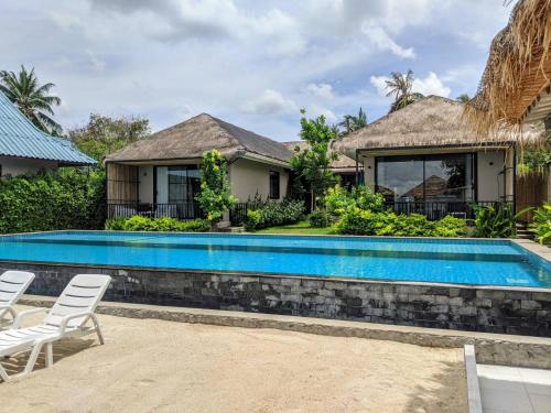 a swimming pool in front of a house at Samutra Residences in Thongsala