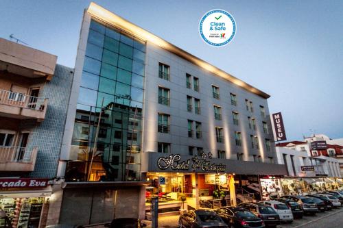 un gran edificio con coches estacionados en un estacionamiento en Hotel 4 Estações, en Fátima