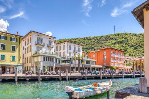 łódź w wodzie obok przystani z budynkami w obiekcie Hotel Lago Di Garda w orbole