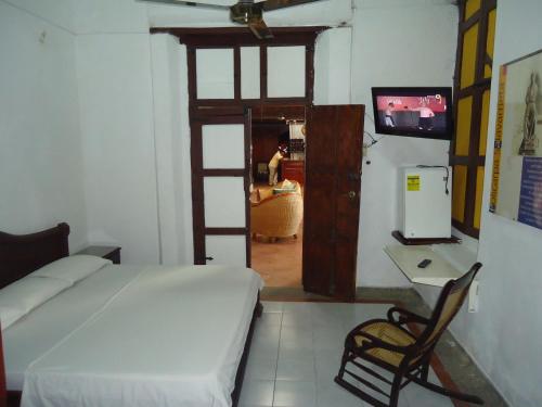 a bedroom with a bed and a desk and a television at Hotel Nueva Granada in Santa Marta