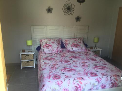 a bedroom with a bed with pink sheets and pillows at Gîte côté jardin in Ingersheim