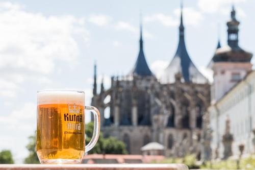 a glass of beer sitting on a table in front of a building at Vila U Varhanáře in Kutná Hora