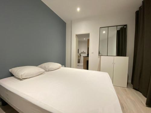 1 dormitorio con 1 cama blanca y 2 almohadas en Gîtes de la Porte Saint Martin, en Châteauroux
