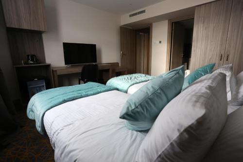 two beds in a hotel room with blue pillows at Hotel Messaoudi in Batna