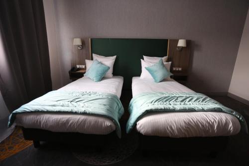 two beds sitting next to each other in a room at Hotel Messaoudi in Batna