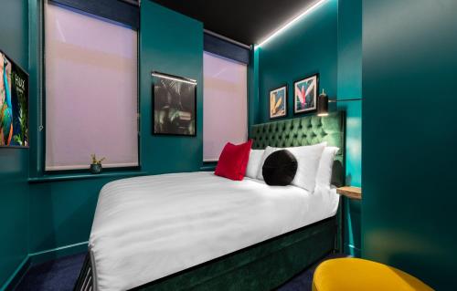 a bedroom with a large white bed with red pillows at Hux Hotel, Kensington in London