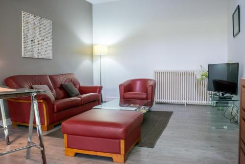 a living room with red furniture and a tv at Gîtes de la Porte Saint Martin in Châteauroux