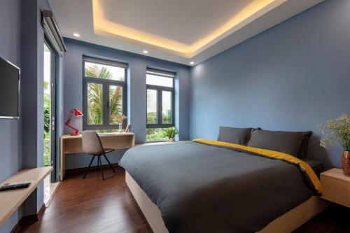 a bedroom with blue walls and a bed and a desk at GH Apartment Westlake - Managed by Pegasy Group in Hanoi