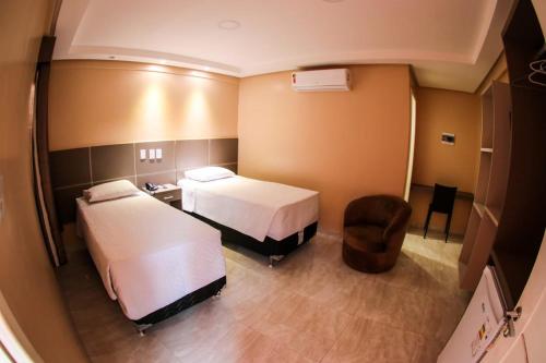 a hotel room with two beds and a chair at Pôr do Sol Hotel in Santarém