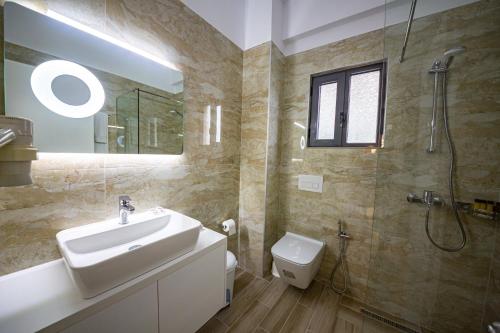 ein Bad mit einem Waschbecken, einer Dusche und einem WC in der Unterkunft Hotel Senator in Sarandë