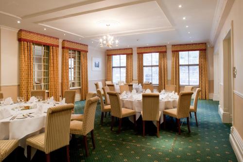 a dining room with tables and chairs and windows at Mercure Salisbury White Hart Hotel & Apartments in Salisbury