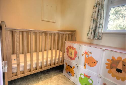 a nursery with a crib andanimal themed wallpaper at The East Wing @ Lower Broom Farm in Kilgetty