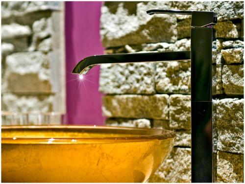 a bathroom with a yellow sink and a water faucet at "Quality Hosts Arlberg Hotel Garni Mössmer" in Sankt Anton am Arlberg