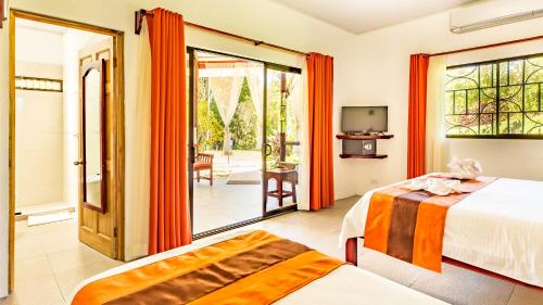 a bedroom with two beds and a sliding glass door at Hotel Villas Rio Mar in Dominical