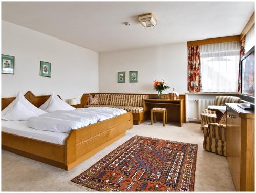 a hotel room with a bed and a couch at "Quality Hosts Arlberg Hotel Garni Mössmer" in Sankt Anton am Arlberg
