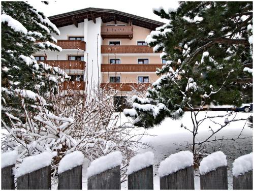 a fence in front of a building covered in snow at "Quality Hosts Arlberg Hotel Garni Mössmer" in Sankt Anton am Arlberg