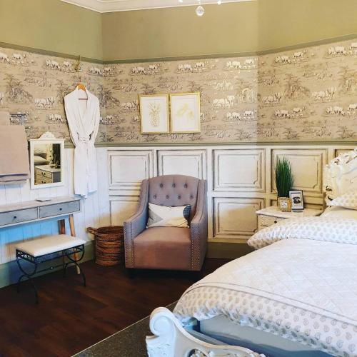a bedroom with a bed and a chair and a dress hanging on a wall at Rigsbys Guesthouse Doncaster in Doncaster