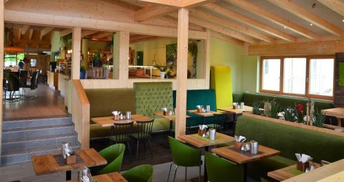 a restaurant with wooden tables and green chairs at Hotel Bergwirt in Herrieden