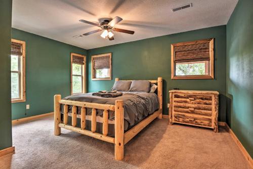 een slaapkamer met een bed en een plafondventilator bij Spacious Log Cabin with Fire Pit and Game Room! in Eureka Springs