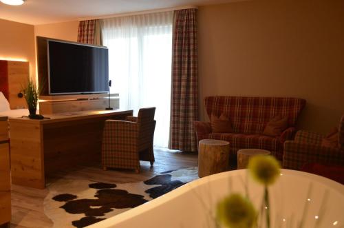 a living room with a tub and a flat screen tv at Hotel Bergwirt in Herrieden
