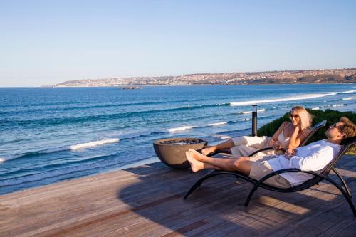 a man and woman sitting in chairs on the beach at African Oceans Manor on the Beach in Mossel Bay