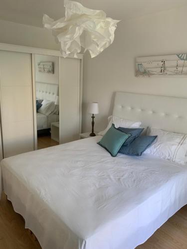 a white bed with blue pillows in a bedroom at Alvor tendance in Alvor