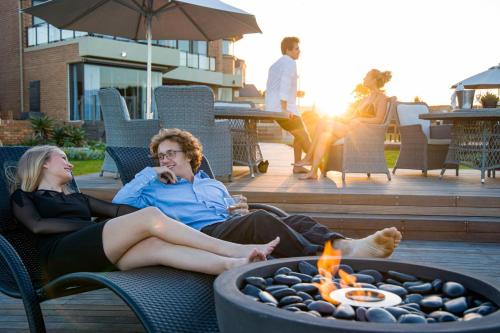 two women sitting in chairs around a fire pit at African Oceans Manor on the Beach in Mossel Bay