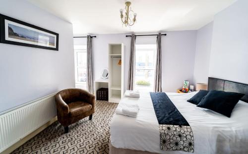 a bedroom with a large bed and a chair at The Cosy Cottage in Moville