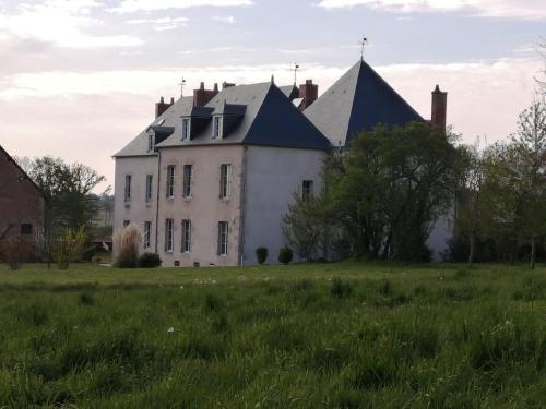 a white house with a blue roof in a field at Chateau de Linard in Linard