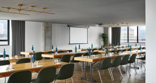 a room with tables and chairs and a projection screen at The Emily Hotel in Chicago