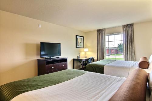 a hotel room with two beds and a flat screen tv at Cobblestone Inn & Suites - Corry in Corry
