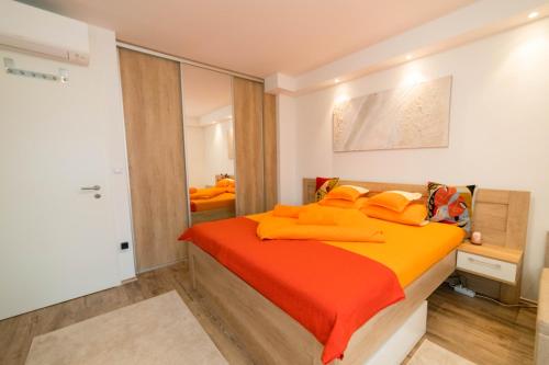 een slaapkamer met een bed met oranje lakens bij Sunset Plage Apartman Fonyód in Fonyód